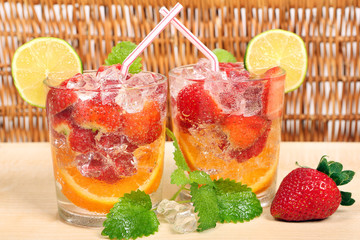 Colored drink with orange, strawberry, lime and ice