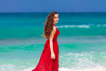 beautiful woman in a red dress  standing on the tropical sea co