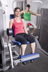 Woman in quadriceps and man in pecs machines