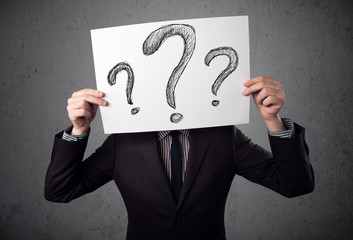 Businessman holding a paper with question marks in front of his