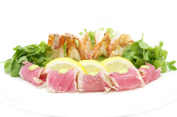 shrimp and tuna with greens and sauce on a white background