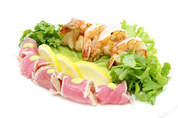 shrimp and tuna with greens and sauce on a white background