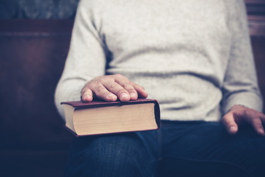 Man sitting with his hand on a book