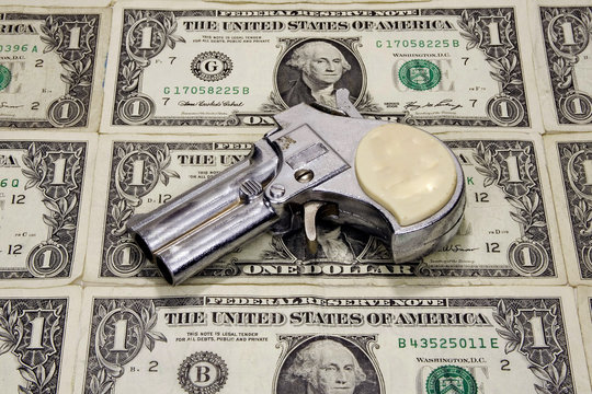 Toy revolver on a sheet on one dollar bills.