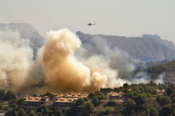 Helicopter in a fire burning mountain forest and village, danger