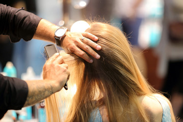 Fototapeta premium Hairdresser combing hair of young girl by hairbrush