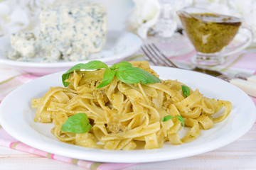 Delicious pasta with pesto on plate on table close-up