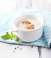Mushroom soup in white pot, on napkin,  on wooden background