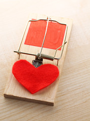 Mousetrap with heart on wooden background