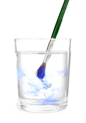 Brush with color paint in glass of water, isolated on white