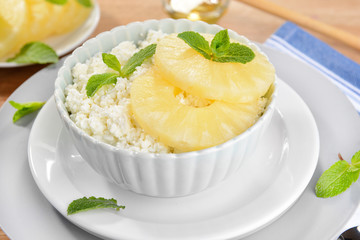 Bowl of tasty cottage cheese with pineapple on wooden table