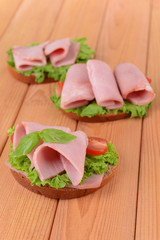 Delicious sandwiches with lettuce and ham on table close-up