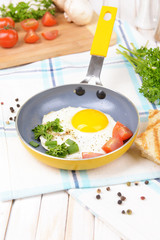 Scrambled eggs and bacon on frying pan on table close-up