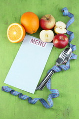 Cutlery tied with measuring tape and menu with fruits