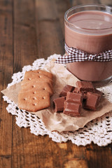 Chocolate milk in glass, on wooden table background