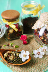 Assortment of herbs and tea in glass jars on wooden background