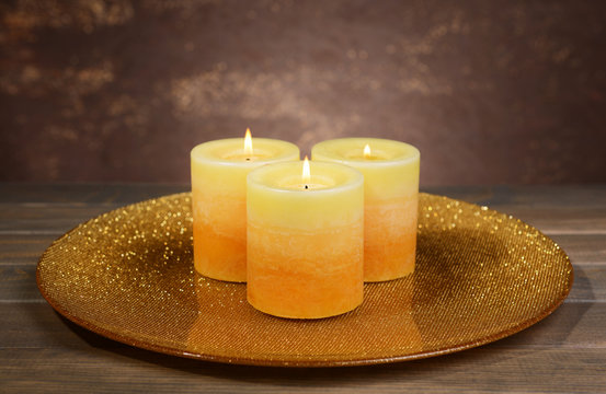 Beautiful candles on table on brown background