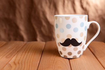 Cup with mustache on table on brown background