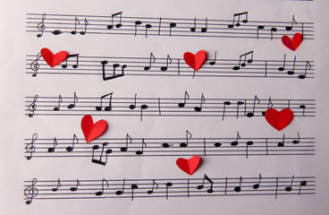 Red paper hearts on music book, close-up