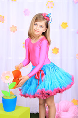 Beautiful small girl in petty skirt watering flowers