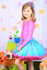 Beautiful small girl in petty skirt on decorative background