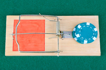 Mousetrap and casino chip on green background