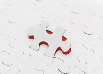 Piece of jigsaw revealing red background. Selective focus