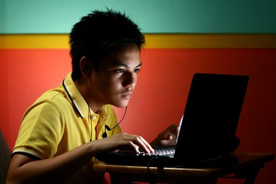 Asian Teen Playing or Working on a Laptop Computer