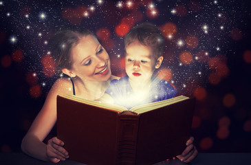 mother and child baby daughter reading magic book in dark