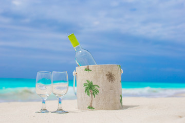 Bottle of white wine and two glasses on the exotic sandy beach