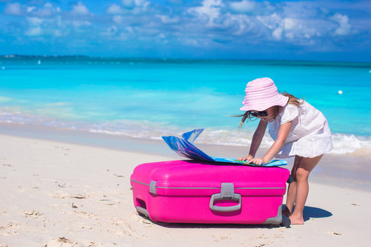 Little adorable girl with big colorful suitcase and a map in