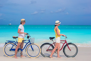Young happy couple riding bikes on white sandy beach