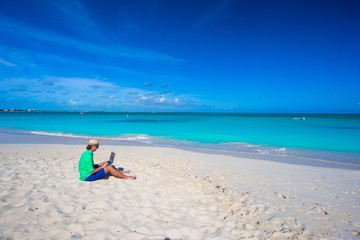 Obraz premium Young man using laptop on tropical beach