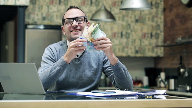 Happy young businessman holding, shaking euro bills, money 