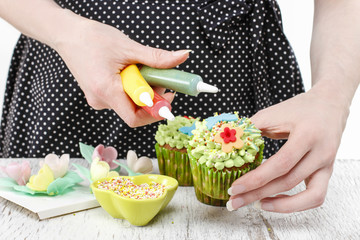 Obraz na płótnie Canvas Woman decorates green fairy cupcakes