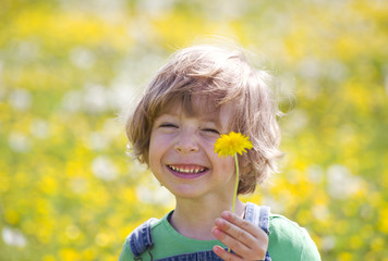 Kind mit Löwenzahn auf einer gelben Wiese