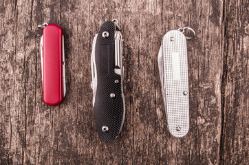 several swiss army knifes on wood in the rainforest
