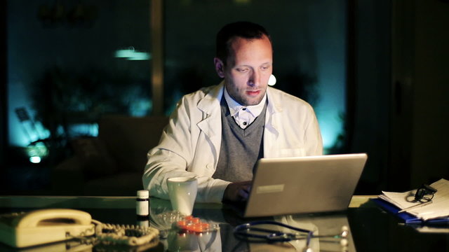 Young Doctor Working On Laptop Computer Late At Night