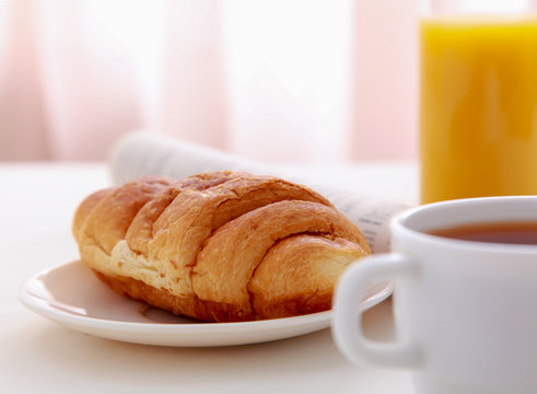 Croissants, Coffee, Orange Juice and Newspapers on table
