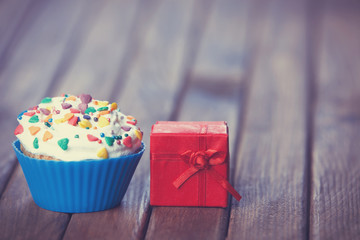 Cupcake and gift box on wooden table