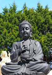 Bouddha noir sur fond de cyprès
