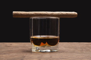 cigar and glass of whiskey on a dark background