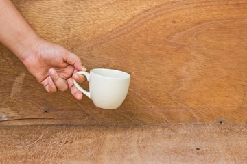 hand give your mug on a wooden floor.