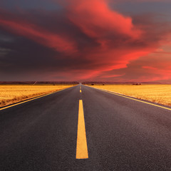 Fototapeta na wymiar Driving on an empty asphalt road at sunset