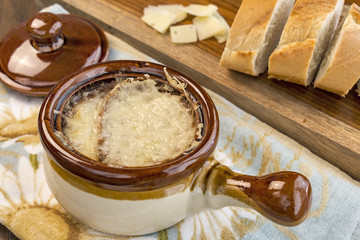 Crock full of traditional French Onion Soup with melted cheese