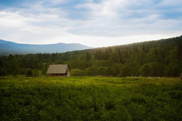 Obraz premium landscape with the house against the wood of mountains and the s