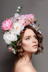 Naklejka premium Beauty portrait of a girl with flowers in her hair on a gray bac