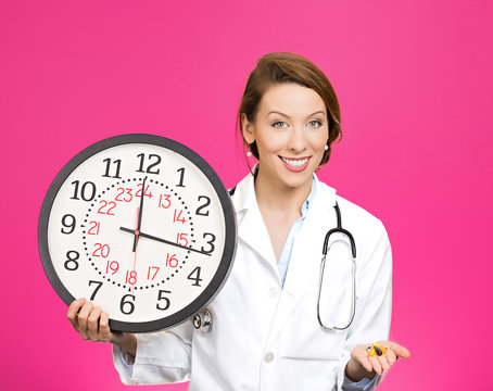 Time for your meds. Doctor holding wall clock and pills