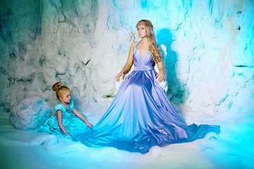 Little girl with mother in princess dress on a background of a w