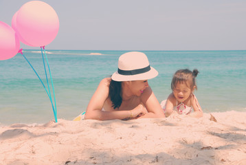 Retro style young mother and  her kid on the beach with pinky ba